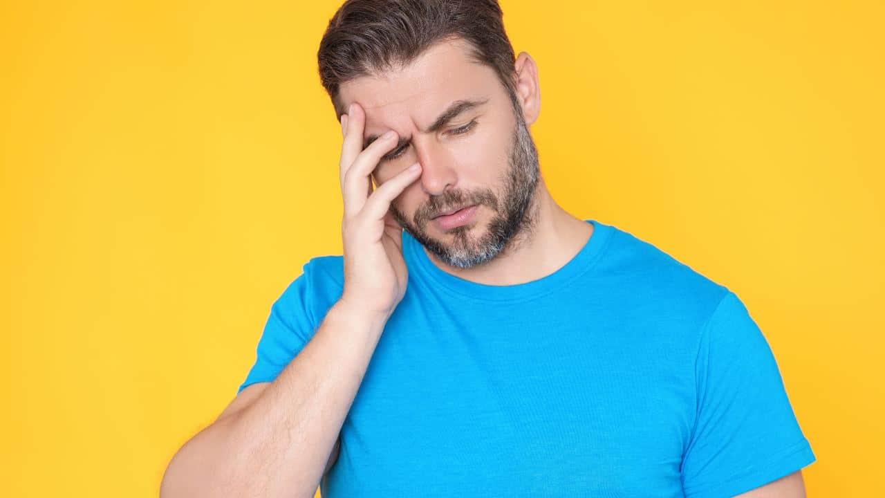 Persona con dolor de cabeza sosteniendo su cabeza con preocupación, reflejando el impacto emocional y físico del problema.
