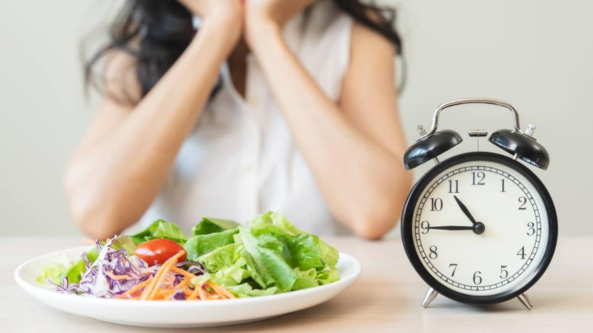 Persona mirando el reloj mientras prepara una ensalada durante su ventana de alimentación