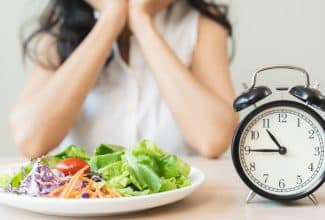 Persona mirando el reloj mientras prepara una ensalada durante su ventana de alimentación