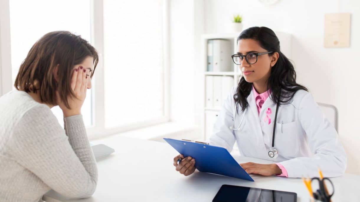 Médico explicando nuevos tratamientos para el cáncer de mama avanzado a una paciente.