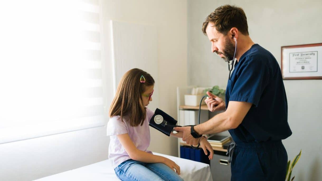Niño en consulta médica midiendo presión arterial con tensiómetro