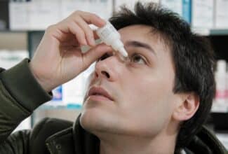 Persona aplicándose gotas para los ojos sin tocar el ojo con el gotero